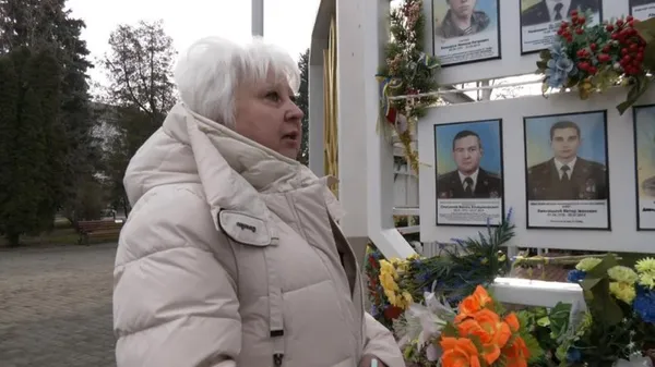 Діана Шевчук біля стенда із фотографіями полеглих військових