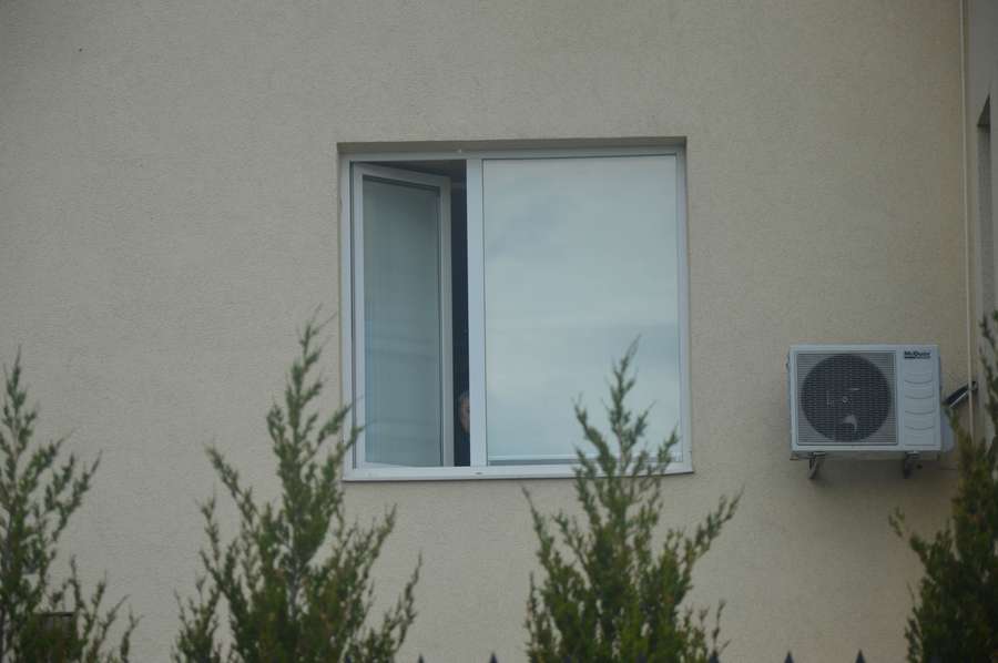 Із вікна на другому поверсі визирає чоловік, схожий на Вєслава Мазура. Помітивши камеру, він одразу сховався