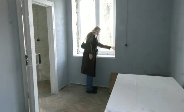 Лілія Костюкова показує вікна, які тричі було пошкоджені через атаки рф