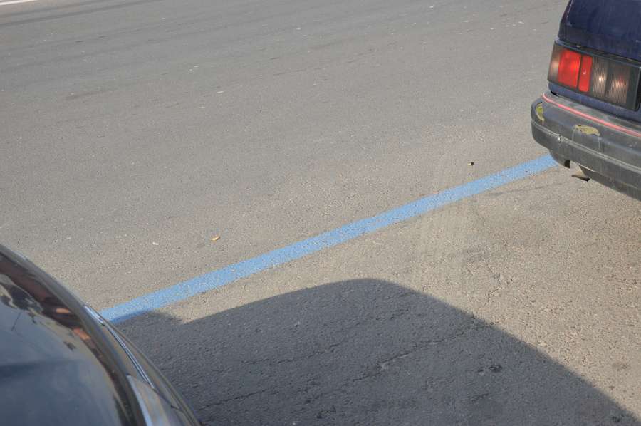Парковку відділено від дороги синьою розміткою