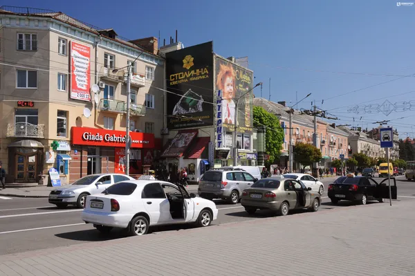 Немасштабне та безсистемне нагромадження реклами на фасаді будинку на центральній вулиці, агресивне поєднання вивіски іноземною мовою та існуючої реклами.